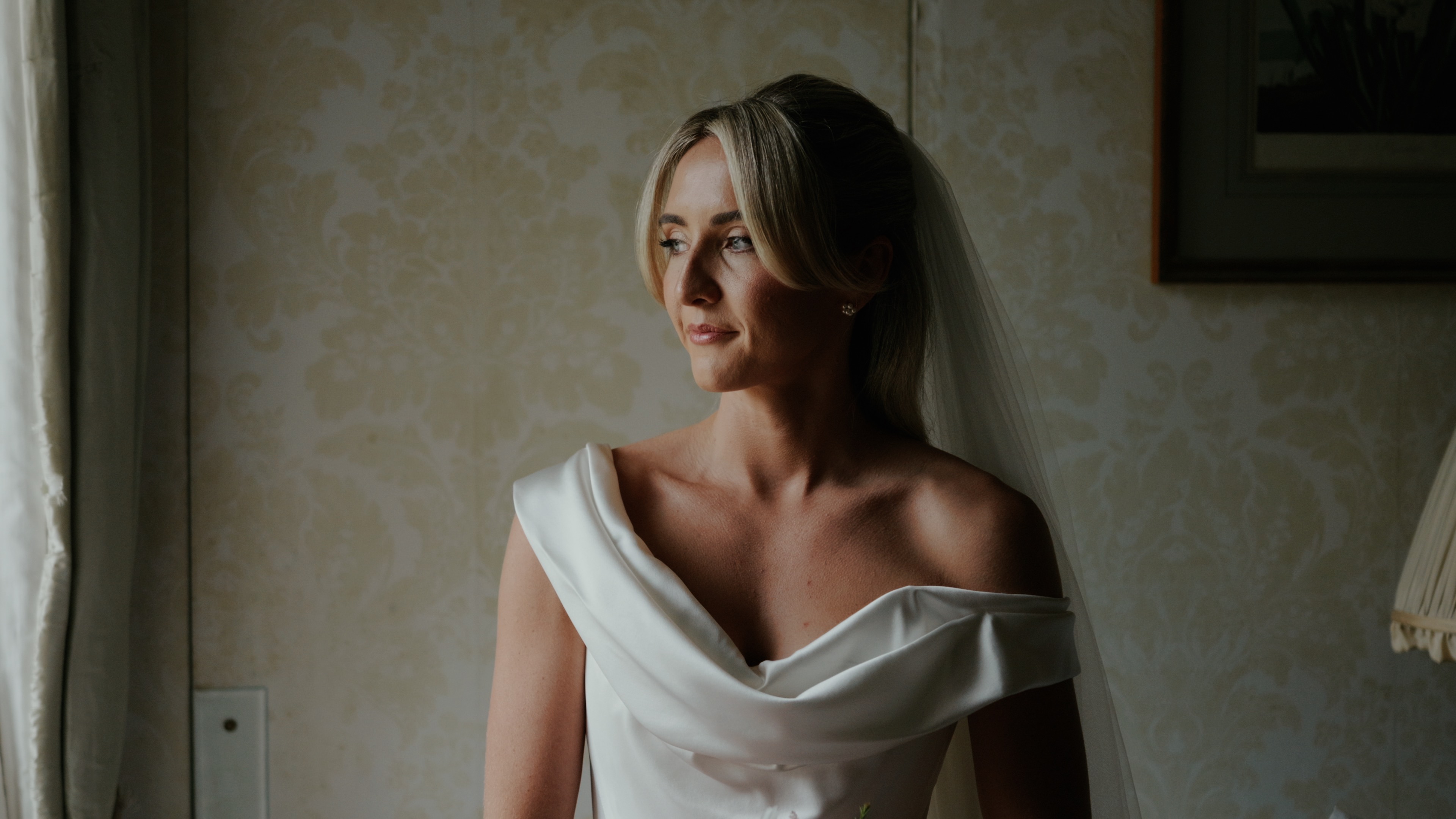 Bride getting ready at window before wedding ceremony